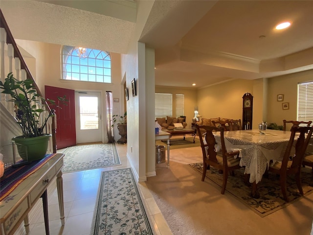 interior space with light tile patterned flooring, a raised ceiling, ornamental molding, and a chandelier