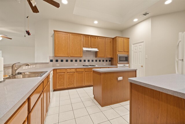 kitchen featuring a center island, white appliances, sink, ceiling fan, and tasteful backsplash