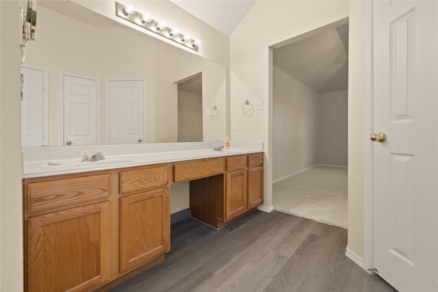 bathroom with vanity, wood-type flooring, and vaulted ceiling