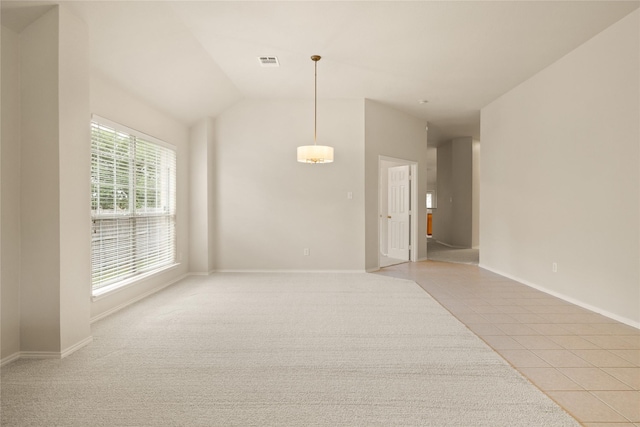 tiled spare room featuring lofted ceiling