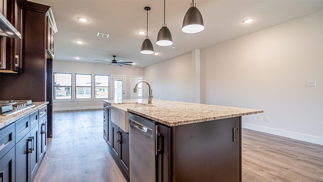 kitchen with sink, dishwasher, hanging light fixtures, dark brown cabinets, and a center island with sink