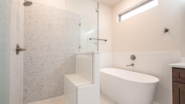 bathroom with vanity, separate shower and tub, and tile walls