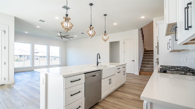 kitchen featuring ceiling fan, stainless steel appliances, pendant lighting, a kitchen island with sink, and white cabinets