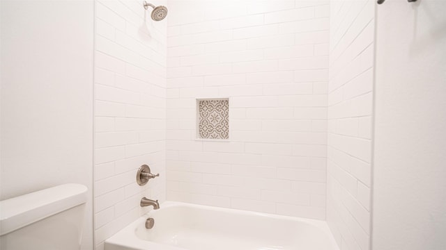 bathroom featuring tiled shower / bath combo and toilet