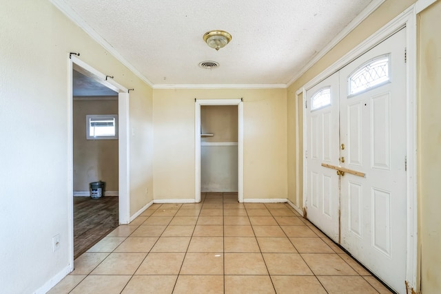 tiled entrance foyer with crown molding and a textured ceiling