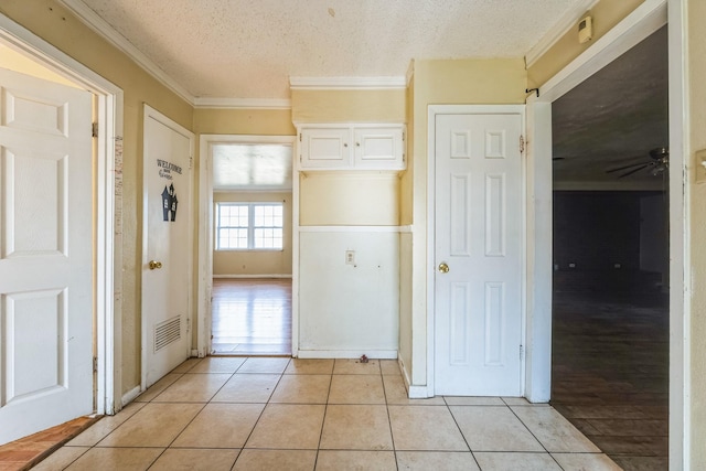 interior space featuring light tile patterned floors, a textured ceiling, and ornamental molding