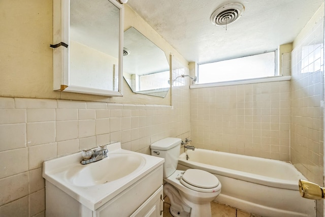 full bathroom with tile patterned floors, toilet, vanity, tile walls, and tiled shower / bath