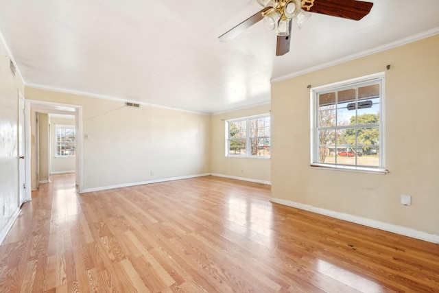 spare room featuring plenty of natural light, light wood-type flooring, and crown molding