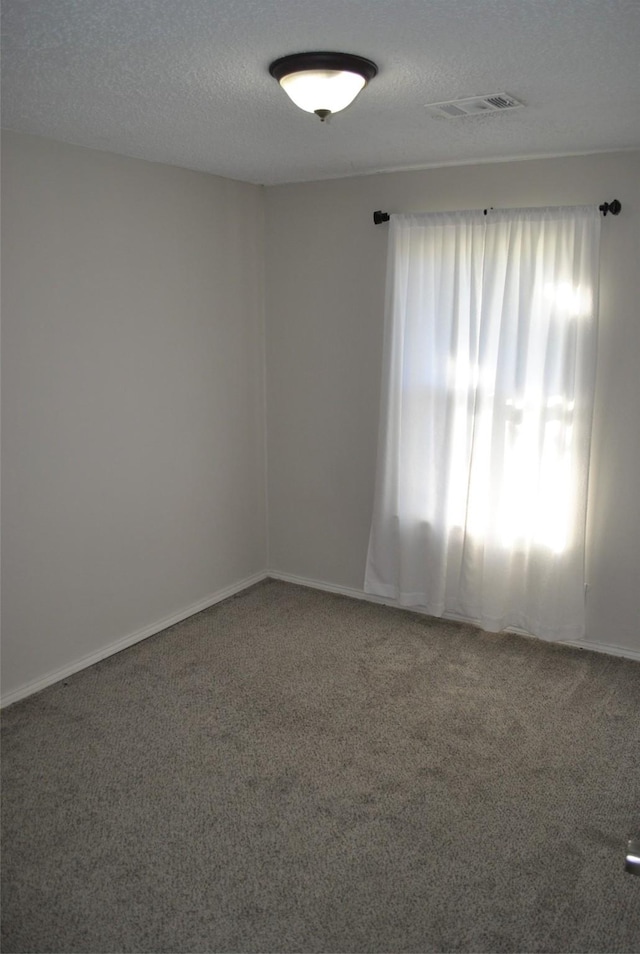 carpeted empty room with a textured ceiling