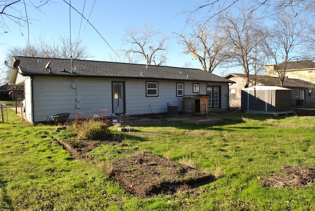 rear view of house featuring a storage unit, central air condition unit, and a yard