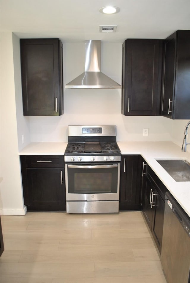 kitchen featuring sink, wall chimney range hood, stainless steel appliances, and light hardwood / wood-style flooring