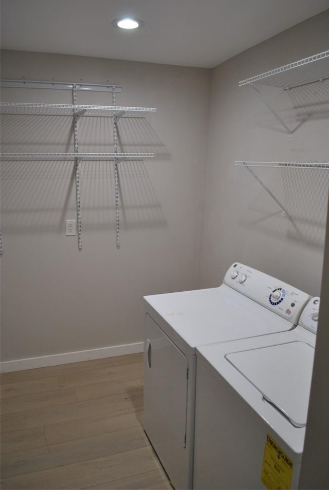 laundry area with washer and clothes dryer and light hardwood / wood-style flooring