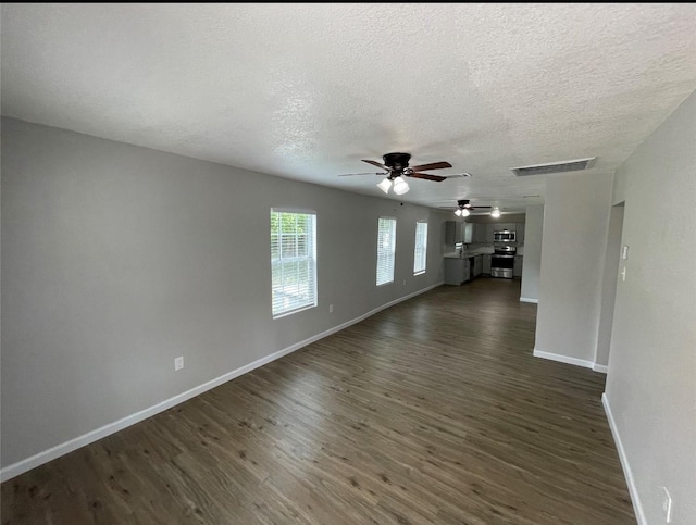 unfurnished living room with dark hardwood / wood-style flooring, a textured ceiling, and ceiling fan