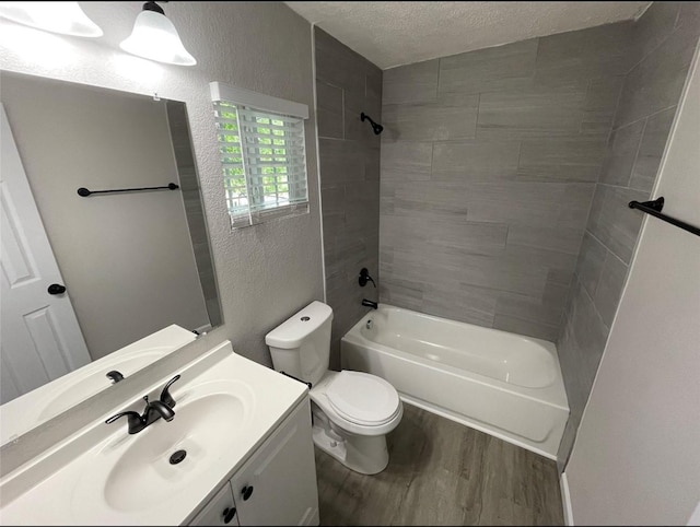 full bathroom featuring wood-type flooring, a textured ceiling, toilet, vanity, and tiled shower / bath