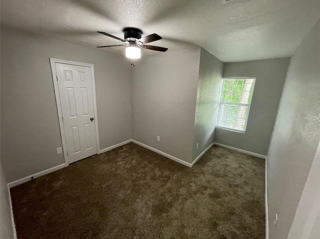 spare room featuring ceiling fan, a textured ceiling, and dark colored carpet