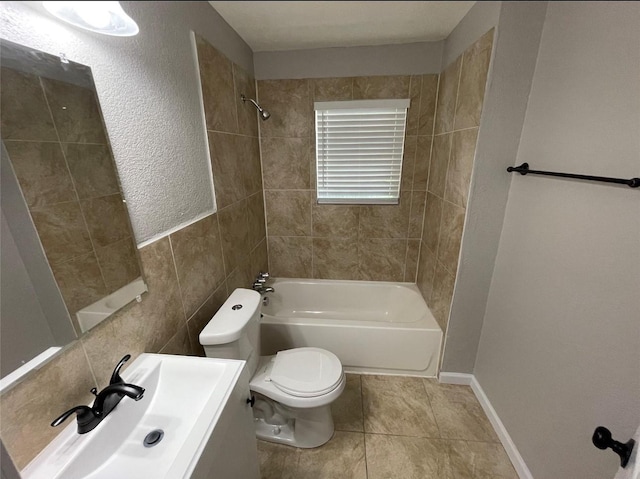 full bathroom featuring sink, tile walls, tile patterned flooring, toilet, and tiled shower / bath