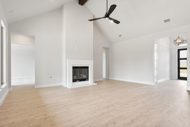 unfurnished living room with high vaulted ceiling, beam ceiling, ceiling fan with notable chandelier, and light hardwood / wood-style flooring