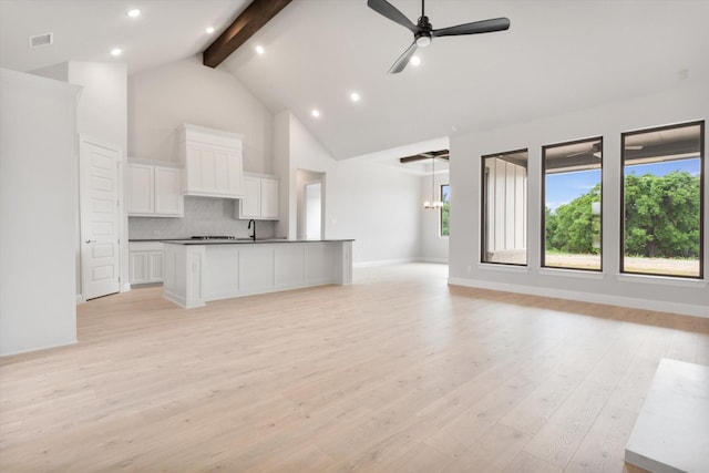 kitchen featuring light hardwood / wood-style flooring, white cabinets, beam ceiling, and a spacious island