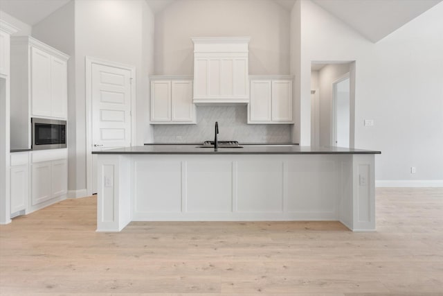 kitchen with white cabinetry, sink, a center island with sink, and built in microwave