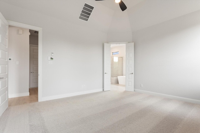 unfurnished bedroom featuring ceiling fan, light colored carpet, connected bathroom, and vaulted ceiling