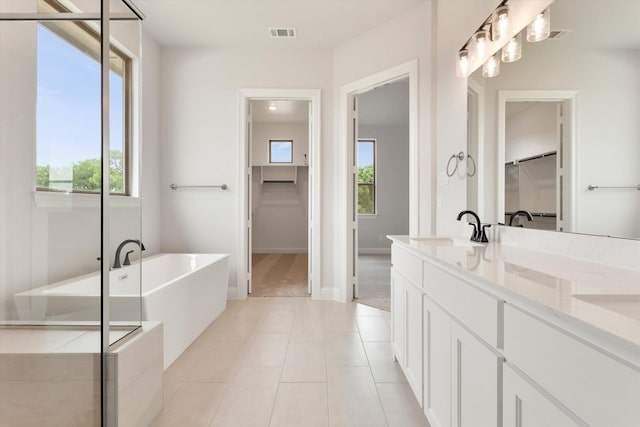 bathroom featuring a washtub, vanity, tile patterned flooring, and a wealth of natural light