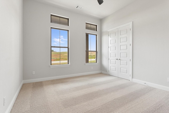 unfurnished bedroom featuring ceiling fan, a closet, and light carpet