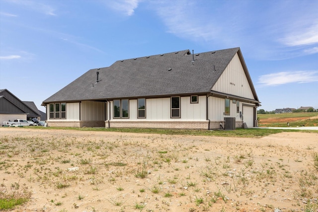 back of property with central AC unit and a garage