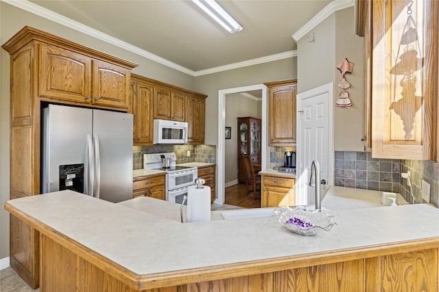 kitchen featuring kitchen peninsula, white appliances, crown molding, and backsplash