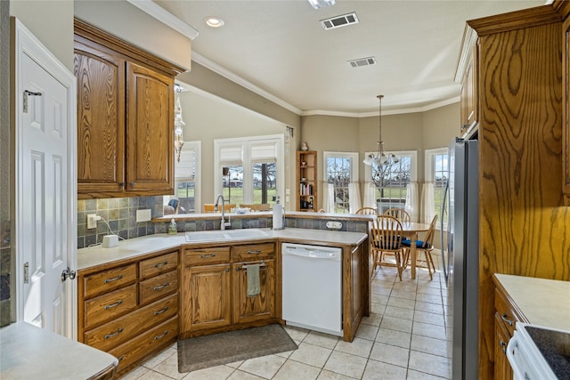 kitchen with pendant lighting, white dishwasher, sink, stainless steel fridge, and a chandelier