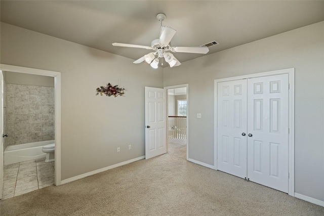 unfurnished bedroom with ceiling fan, light colored carpet, connected bathroom, and a closet