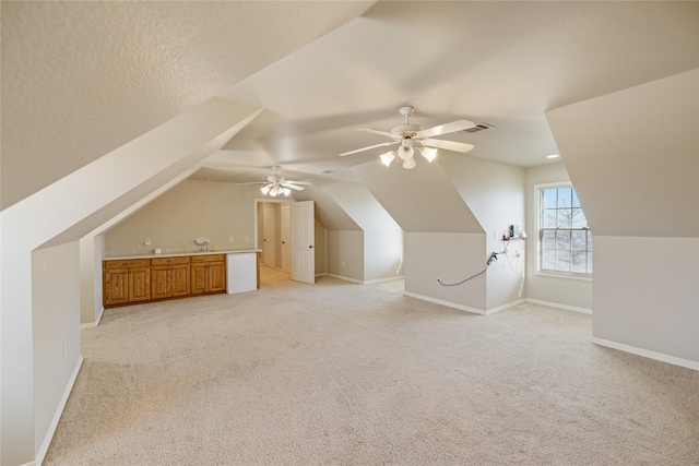 bonus room featuring a textured ceiling, light colored carpet, vaulted ceiling, and ceiling fan