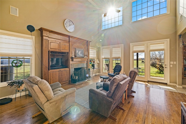 living room featuring a fireplace, a towering ceiling, and dark hardwood / wood-style floors