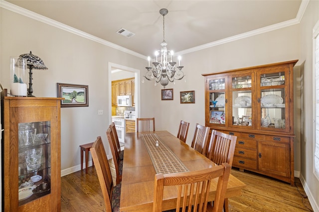 dining room featuring hardwood / wood-style floors, ornamental molding, and a notable chandelier