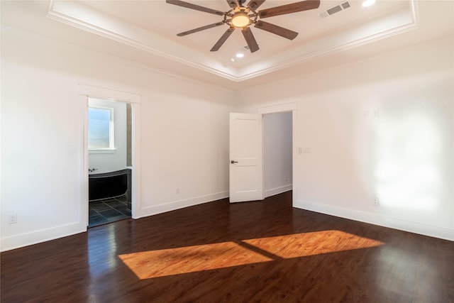 unfurnished room with dark wood-type flooring, a tray ceiling, and crown molding