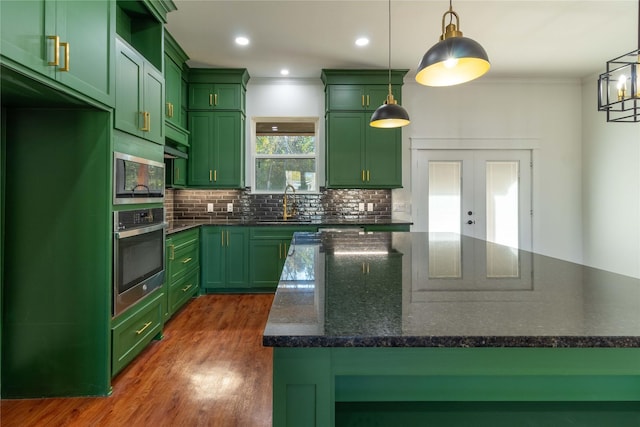 kitchen with dark stone countertops, appliances with stainless steel finishes, pendant lighting, and green cabinets