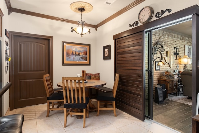 dining space with light tile patterned floors, brick wall, and crown molding