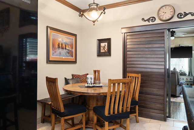 tiled dining room featuring ceiling fan and crown molding