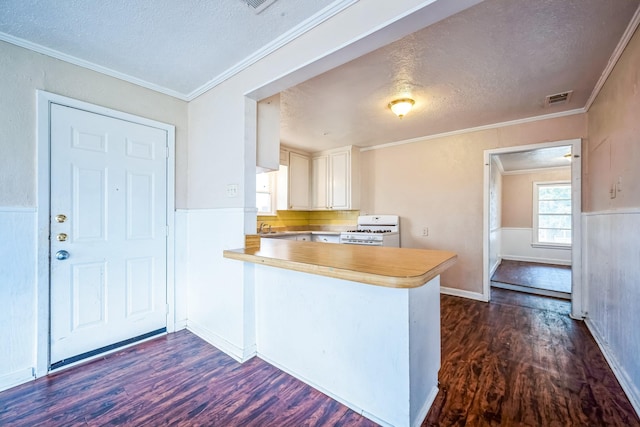 kitchen featuring white gas stove, dark wood-type flooring, kitchen peninsula, a textured ceiling, and white cabinets