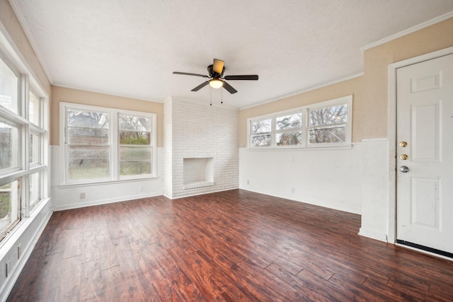 unfurnished living room featuring a brick fireplace, ceiling fan, a healthy amount of sunlight, and crown molding