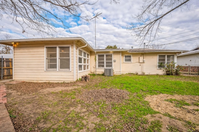 rear view of house featuring central AC unit and a yard