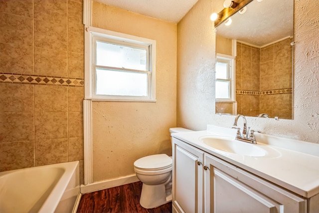 full bathroom with wood-type flooring, tiled shower / bath, vanity, and toilet