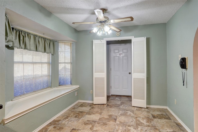 bathroom with ceiling fan and a textured ceiling