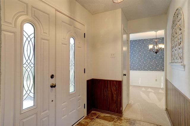 foyer featuring wooden walls, radiator heating unit, a chandelier, and a textured ceiling