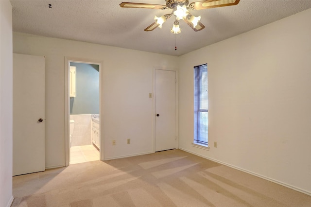 empty room with ceiling fan, light colored carpet, and a textured ceiling