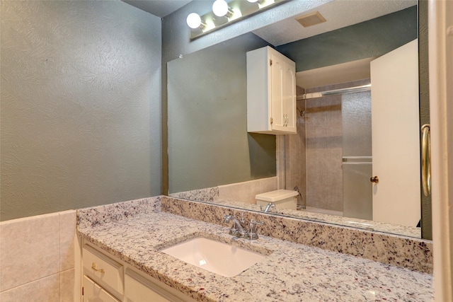 bathroom with vanity, a shower with door, and tile walls