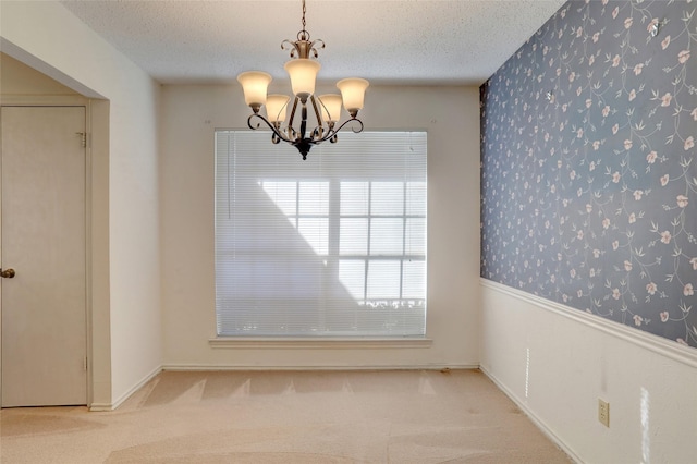 unfurnished dining area with a healthy amount of sunlight, a textured ceiling, and an inviting chandelier