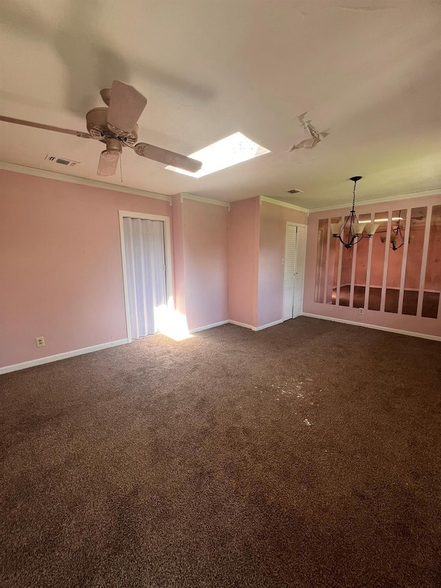 carpeted spare room with ceiling fan with notable chandelier, ornamental molding, and a skylight