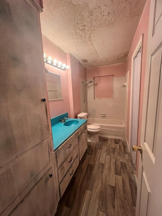 full bathroom with a textured ceiling, toilet, vanity, shower / bathtub combination, and hardwood / wood-style flooring