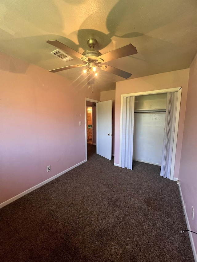 unfurnished bedroom with ceiling fan, a closet, and dark colored carpet