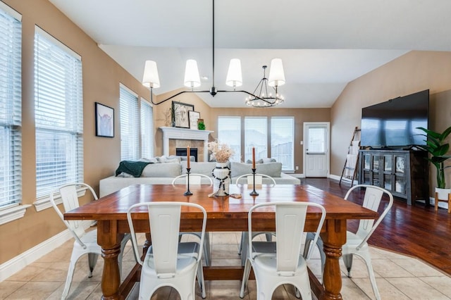 dining area featuring light tile patterned floors, lofted ceiling, and a notable chandelier